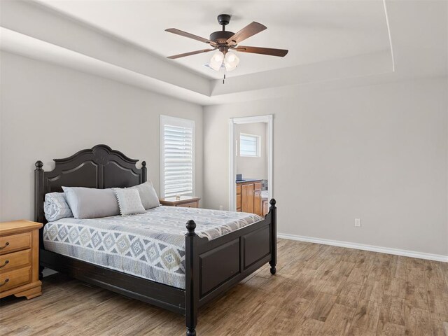 bedroom featuring hardwood / wood-style floors, ceiling fan, and a tray ceiling