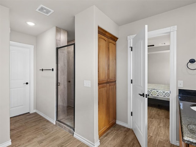 bathroom with wood-type flooring and a shower with door