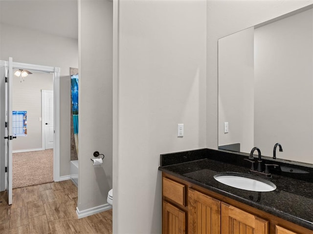 full bathroom featuring vanity, shower / tub combo with curtain, ceiling fan, hardwood / wood-style flooring, and toilet