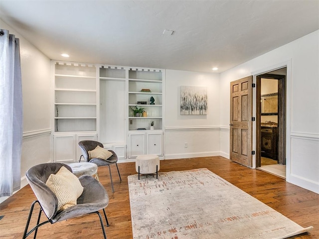 living area featuring built in features and wood-type flooring