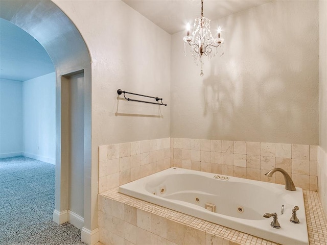 bathroom with a notable chandelier and tiled tub