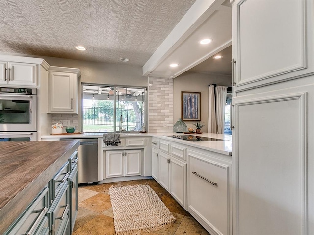 kitchen with white cabinetry, tasteful backsplash, butcher block countertops, a textured ceiling, and appliances with stainless steel finishes