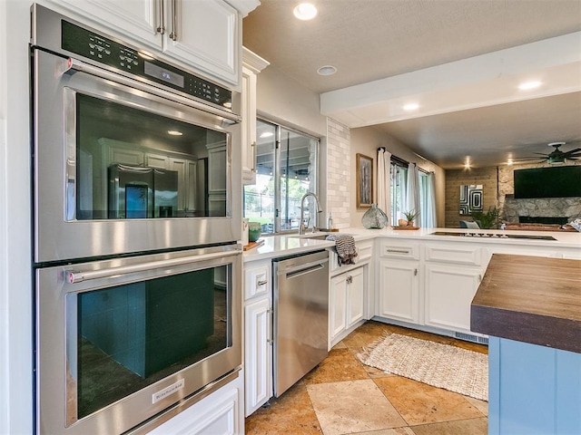 kitchen with white cabinetry, sink, ceiling fan, stainless steel appliances, and kitchen peninsula