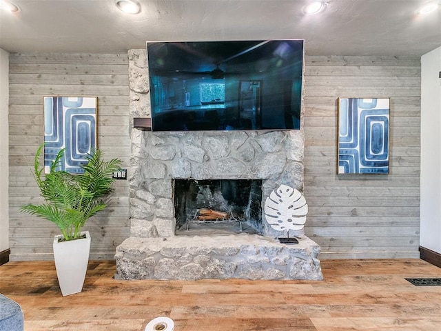 details with a fireplace, wood-type flooring, and wooden walls