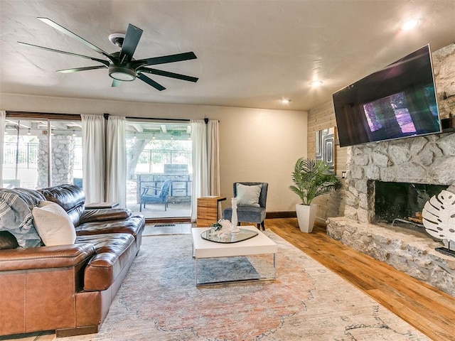 living room with a fireplace, ceiling fan, and light hardwood / wood-style flooring