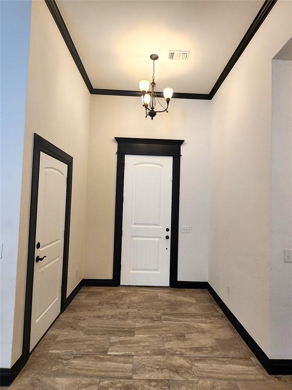 entrance foyer featuring hardwood / wood-style flooring, ornamental molding, and a notable chandelier