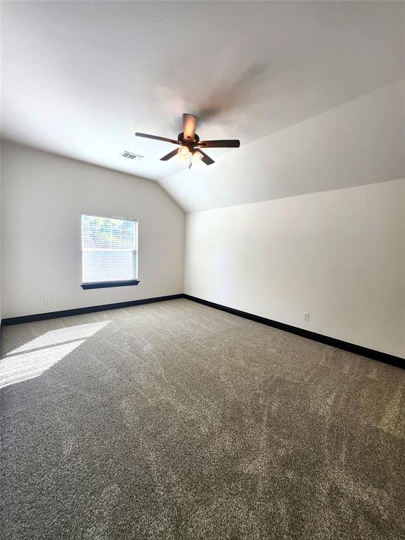 additional living space featuring ceiling fan, carpet, and lofted ceiling