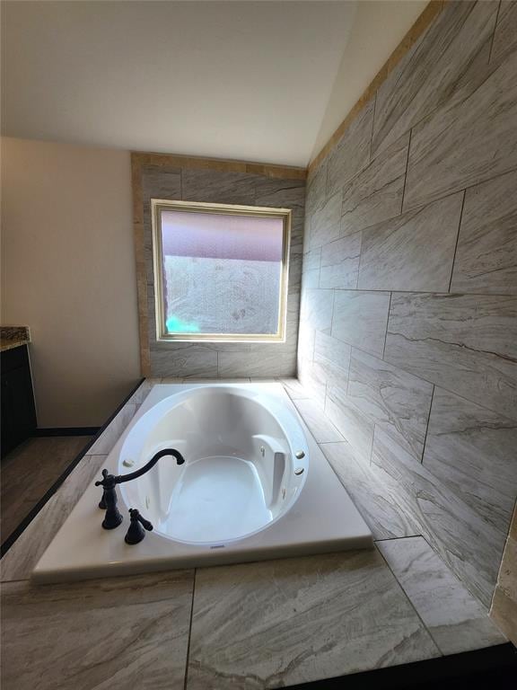 bathroom featuring lofted ceiling and tiled bath