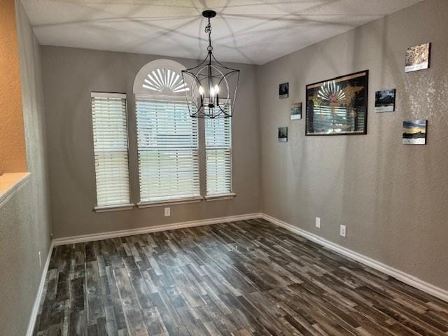 unfurnished dining area with plenty of natural light, dark hardwood / wood-style flooring, and an inviting chandelier