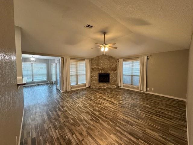 unfurnished living room featuring dark hardwood / wood-style floors, plenty of natural light, a fireplace, and vaulted ceiling