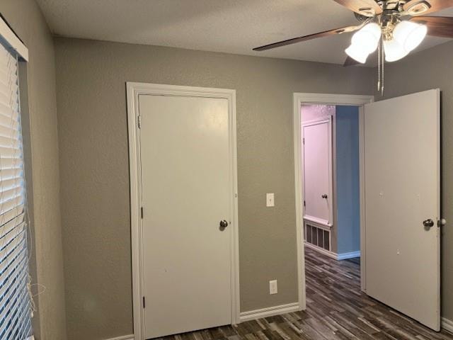 unfurnished bedroom with ceiling fan and dark wood-type flooring