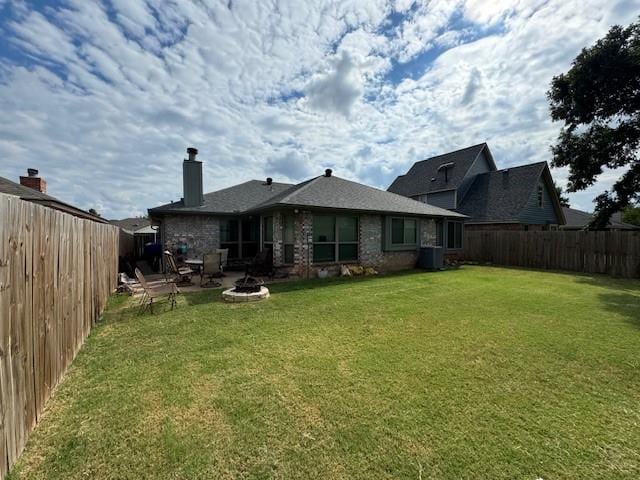 back of house featuring a fire pit, cooling unit, and a yard