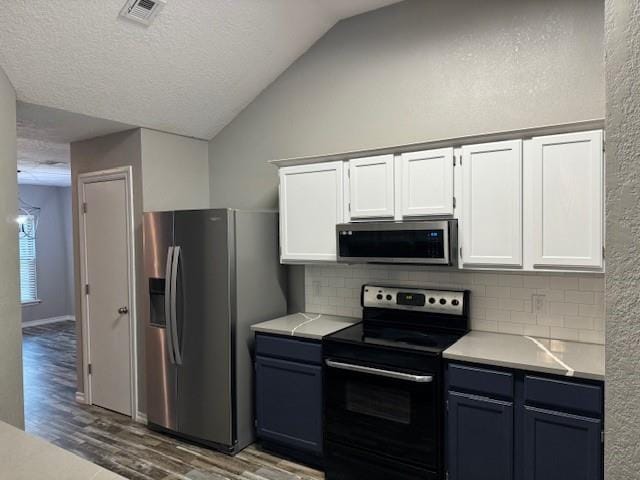 kitchen with lofted ceiling, decorative backsplash, light wood-type flooring, appliances with stainless steel finishes, and white cabinetry