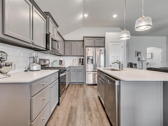 kitchen featuring sink, hanging light fixtures, stainless steel appliances, lofted ceiling, and decorative backsplash