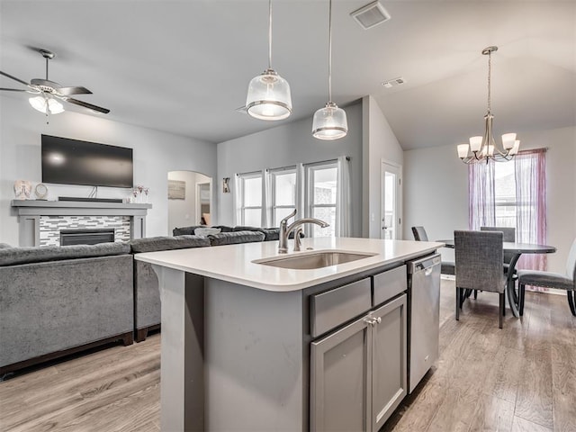 kitchen featuring pendant lighting, stainless steel dishwasher, sink, and an island with sink