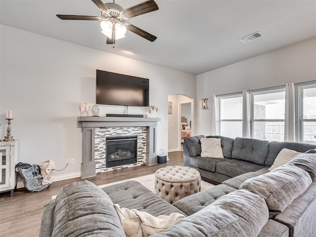 living room with a tile fireplace, hardwood / wood-style floors, and ceiling fan