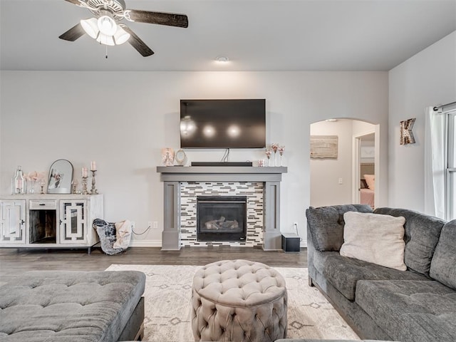 living room featuring hardwood / wood-style floors, ceiling fan, and a tiled fireplace