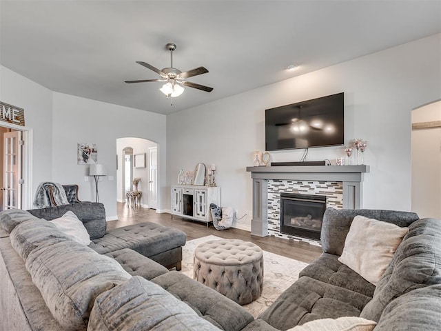 living room featuring a tile fireplace, ceiling fan, and wood-type flooring