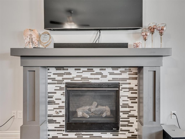 interior details featuring backsplash, ceiling fan, and a fireplace