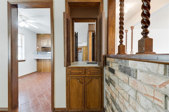 hall featuring light wood-type flooring and a textured ceiling