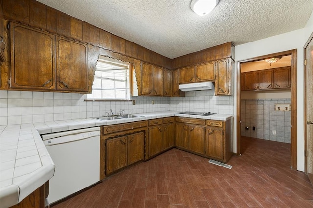 kitchen featuring dishwasher, sink, black cooktop, tile counters, and dark hardwood / wood-style flooring