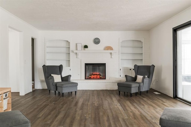 living area featuring a fireplace, a textured ceiling, dark hardwood / wood-style flooring, and built in features