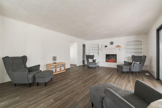 living room featuring built in features, dark hardwood / wood-style flooring, and a textured ceiling