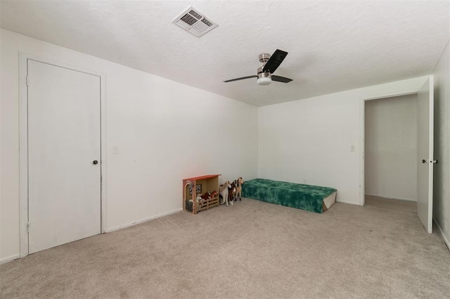 interior space featuring light carpet, a textured ceiling, and ceiling fan