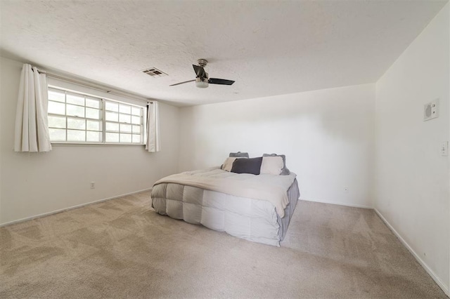 carpeted bedroom featuring ceiling fan and a textured ceiling