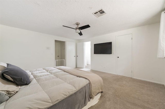 bedroom featuring ceiling fan, light colored carpet, and a textured ceiling