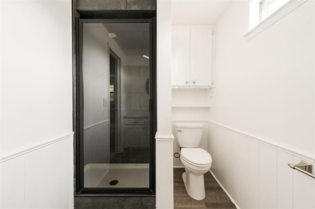 bathroom featuring wood-type flooring, toilet, and an enclosed shower