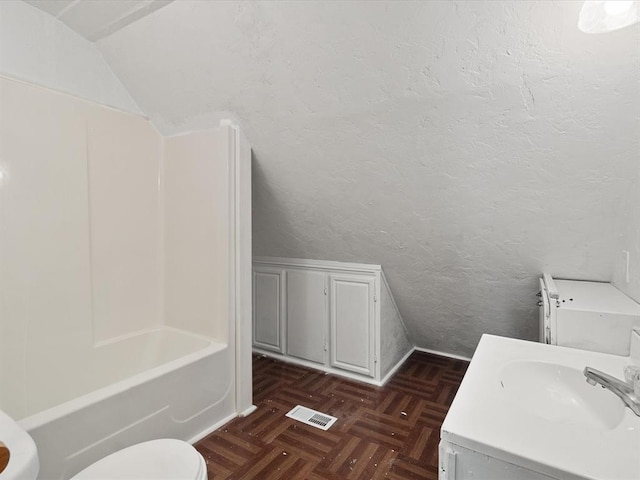 bathroom featuring vanity, toilet, parquet floors, and lofted ceiling