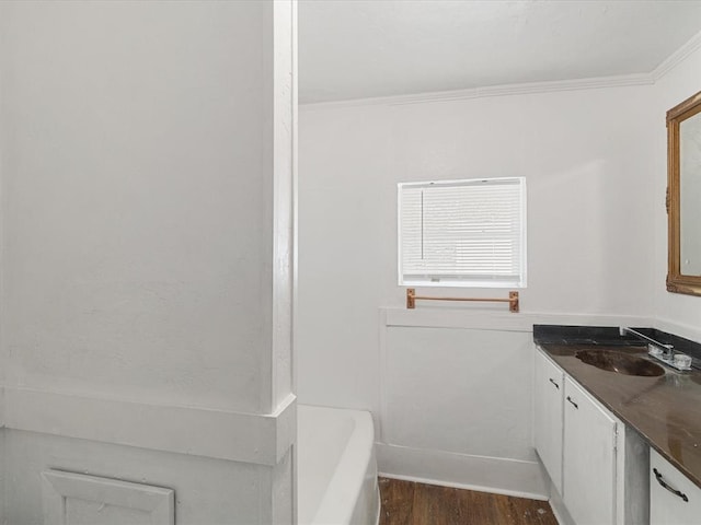 bathroom featuring a tub, hardwood / wood-style floors, vanity, and ornamental molding