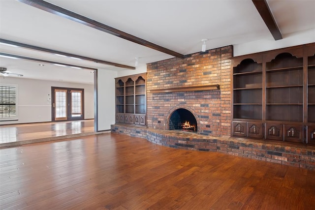 unfurnished living room featuring beam ceiling, a fireplace, french doors, and wood-type flooring