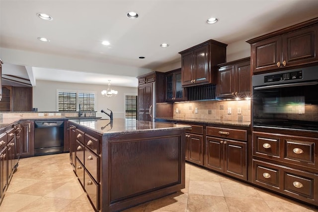 kitchen featuring dark brown cabinets, a center island with sink, decorative backsplash, and black appliances