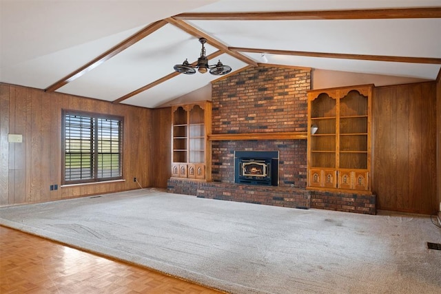 unfurnished living room with ceiling fan, carpet, vaulted ceiling with beams, and wooden walls