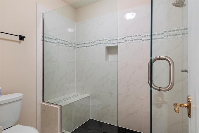 bathroom with a shower with shower door and toilet