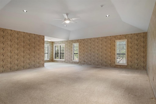 carpeted spare room featuring ceiling fan and vaulted ceiling