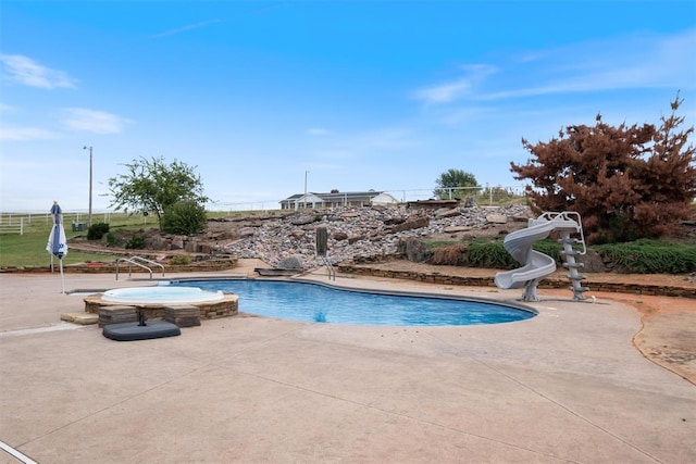 view of pool with an in ground hot tub, a water slide, and a patio area