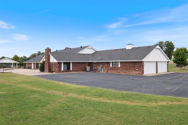 view of front of house with a garage, a front yard, and central air condition unit