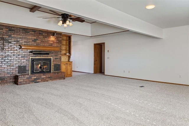 unfurnished living room featuring ceiling fan, a brick fireplace, carpet, and beam ceiling