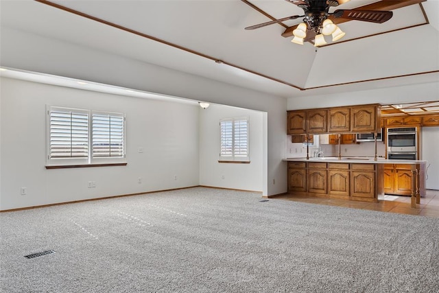 kitchen with lofted ceiling, light colored carpet, ceiling fan, and stainless steel appliances