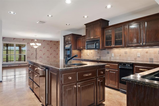 kitchen with dark brown cabinetry, sink, decorative light fixtures, an island with sink, and black appliances