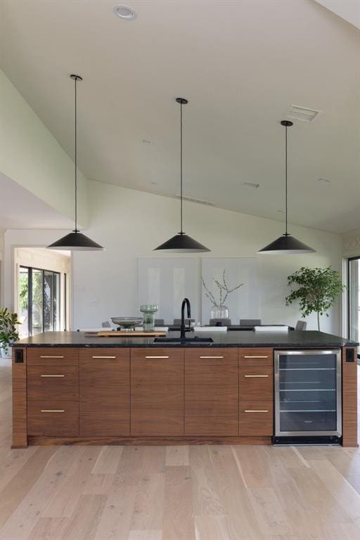 bar featuring a sink, light wood-style flooring, high vaulted ceiling, and beverage cooler