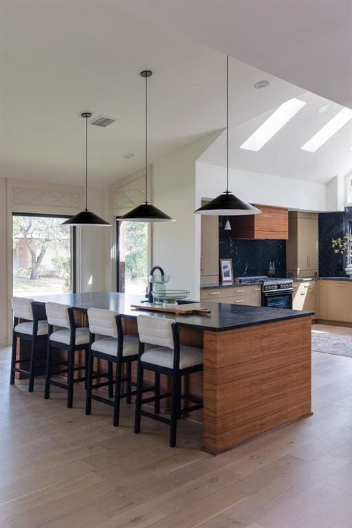 kitchen featuring a spacious island, visible vents, gas range oven, decorative backsplash, and modern cabinets