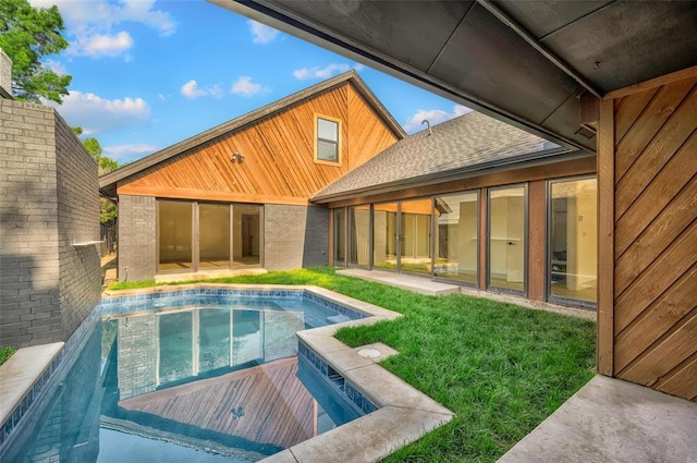 rear view of property with an outdoor pool, a patio, a lawn, and roof with shingles