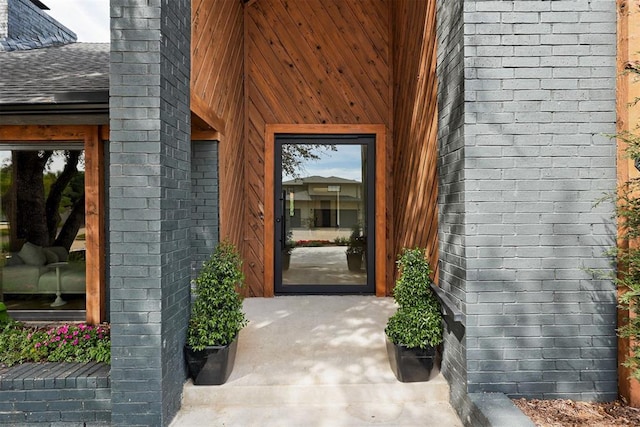 property entrance with brick siding and roof with shingles