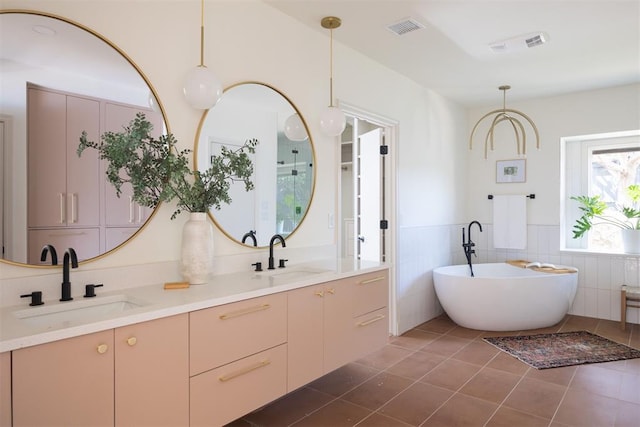 bathroom featuring a sink, visible vents, a freestanding bath, and tile patterned flooring