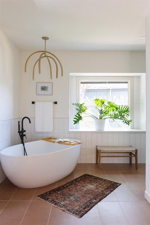 full bathroom featuring tile patterned flooring, a soaking tub, wainscoting, and tile walls