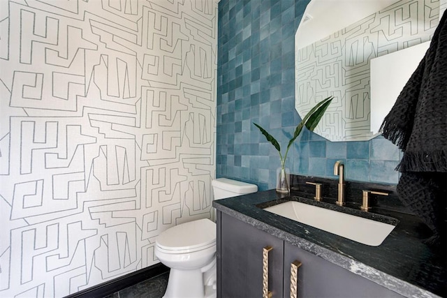 half bathroom featuring vanity, tile walls, toilet, and tasteful backsplash